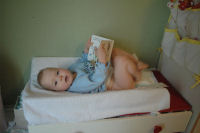 Alexandra reads a book while she gets a clean diaper