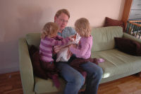 Dad holds Madeleine and Caroline and Alexandra are watching