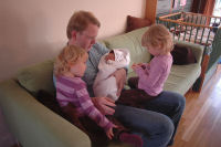 Dad holds Madeleine and Caroline and Alexandra are watching