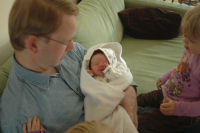 Dad holds Madeleine and Caroline and Alexandra are watching