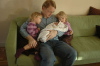 Dad holds Madeleine and Caroline and Alexandra are watching