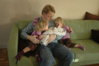 Dad holds Madeleine and Caroline and Alexandra are watching